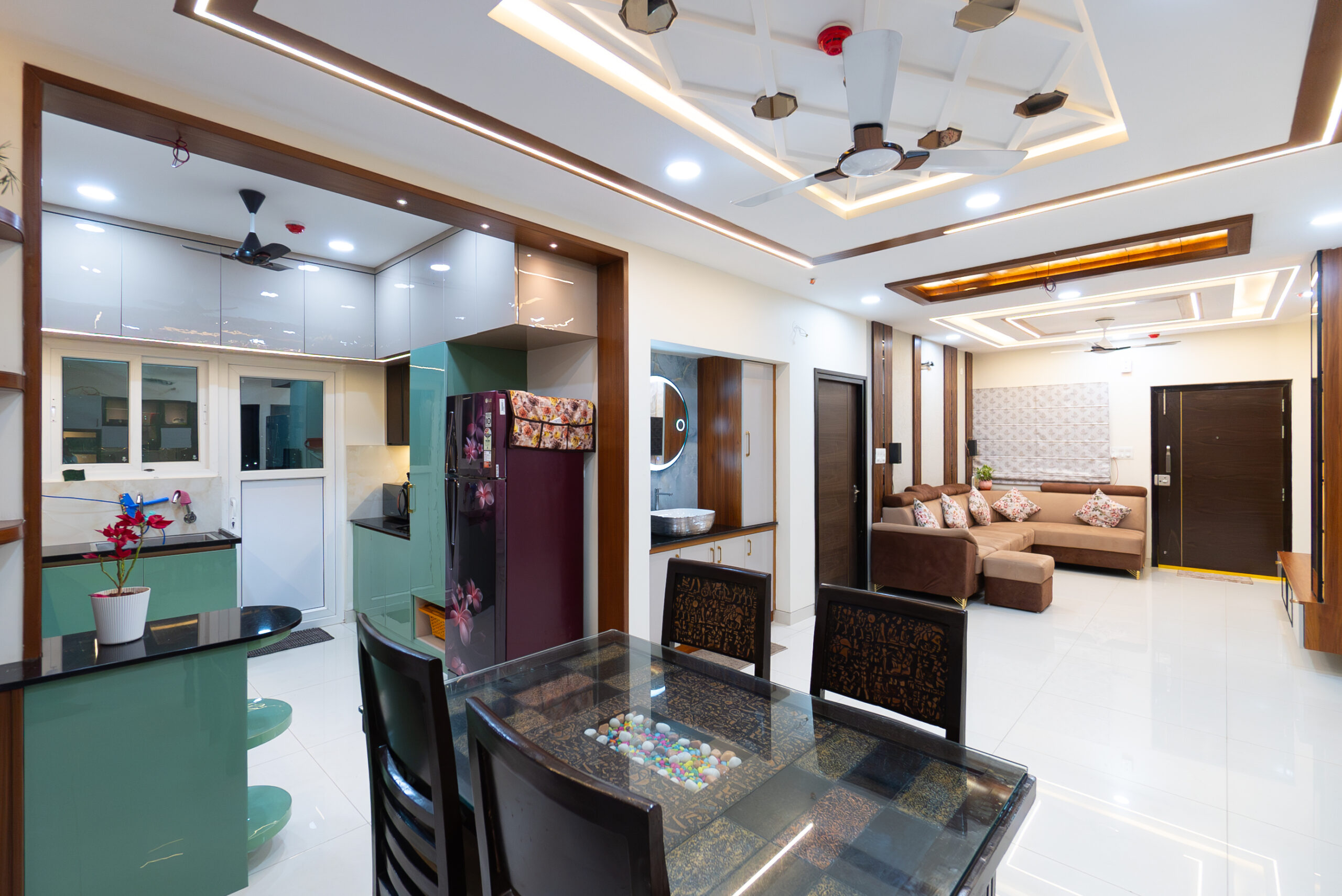 Spacious living and dining area showcasing luxury villa interiors in Hyderabad with modular kitchen, designer ceiling lighting, elegant sofa setup, and premium finishes.